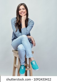 Smiling Woman Sitting On Hi Stool. Isolated Studio Portrait With Gray Background.