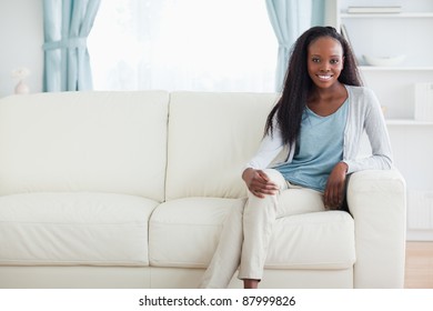 Smiling Woman Sitting On Sofa With Legs Crossed