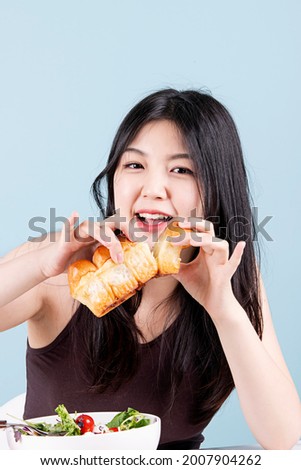 Smiling woman sitting at the table and eating bread for breakfast