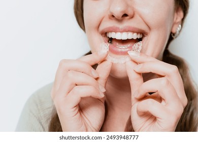 Smiling woman with a snow-white smile demonstrate clear teeth aligner for orthodontal straightening teeth treatment - Powered by Shutterstock