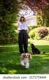 Smiling Woman Standing At The Backyard With Her Cute Puppies. 