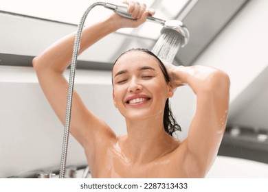 Smiling Woman Taking Shower Posing With Eyes Closed Washing Body And Hair In Modern Bathroom Indoor. Female Holding Showerhead With Running Water. Wellness And Spa. Selective Focus - Powered by Shutterstock