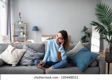 Smiling Woman Talking On The Phone At Home On The Sofa. Feminine Gossip On The Smartphone.