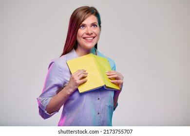 Smiling woman teacher or adult female student holding open yellow book. girl looking away. isolated female portrait on gray background