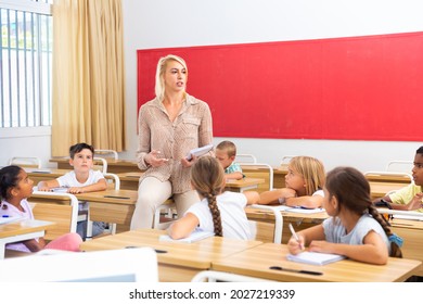 Smiling Woman Teacher Explaining New Theme To Children During Class