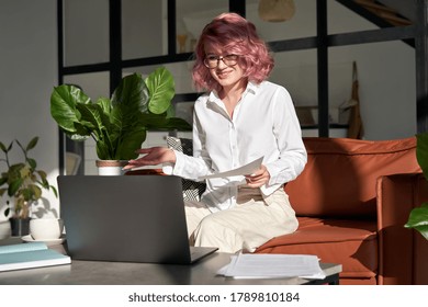 Smiling Woman Teacher Videoconferencing By Webcam Conference On Laptop. Young Hipster Lady With Pink Hair Communicating Online Working Learning Or Teaching From Home Office In App Online.