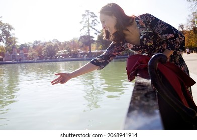 Smiling Woman Throwing Food To Fish And Ducks