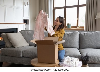 Smiling woman unpack parcel box with delivered online fashion store clothes, check blouse quality, feel satisfied by received apparels. Client of e-commerce webstore, express delivery services concept - Powered by Shutterstock