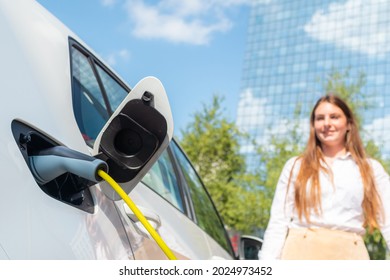 Smiling Woman Unplugging The Electric Car Charger At A Downtown Charging Point