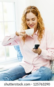 Smiling Woman Using Cordless Phone And Drinking Coffee