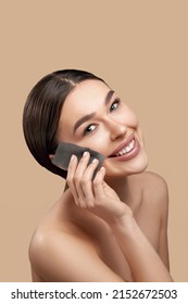  Smiling woman using facial oil blotting paper portrait. Closeup of beautiful happy girl model with natural makeup using oil absorbing sheets. Face skin care