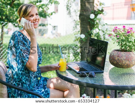Smiling woman using her smart phone while sitting at cafe garden