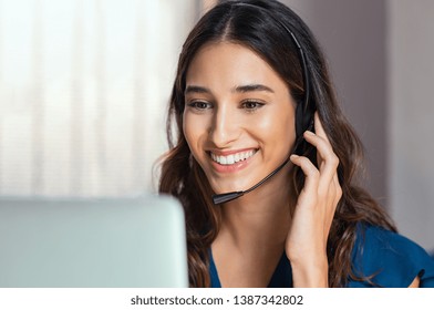 Smiling woman using laptop while talking to customer on phone. Consulting corporate client in conversation with customer using computer. Service desk consultant talking in a call center.