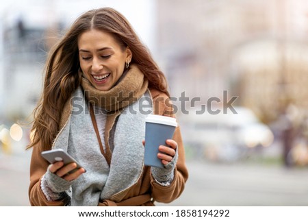 Smiling woman using mobile phone while having a coffee

