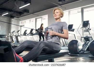 Smiling woman using seated press machine in gym - Powered by Shutterstock