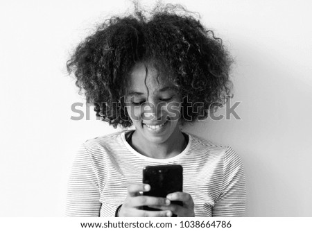 Similar – Serious black woman with afro hair looking at her smart phone outdoors.