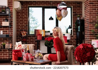 Smiling Woman With Valentines Day Expensive Gifts In Living Room, Beautiful Blonde Girl In Red Dress With Luxury Present Boxes, Bear Soft Toy, Flowers, Balloons. February 14 Romantic Surprises