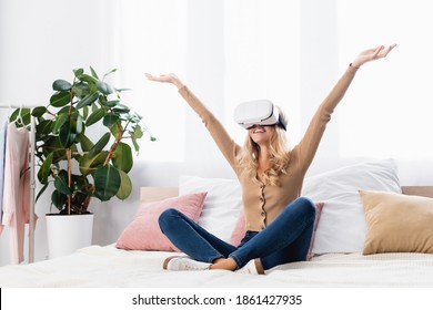 Smiling Woman In Vr Headset Sitting On Bed At Home