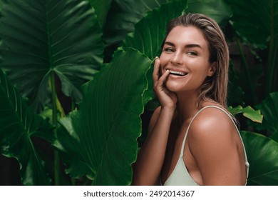 Smiling woman with wet hair surrounded by lush tropical leaves. - Powered by Shutterstock