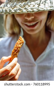 Smiling Woman In A White Shirt And A Straw Hat Holding A Slice Of Fried Tempeh. Portrait Picture. Concept Of Healthy Eating.