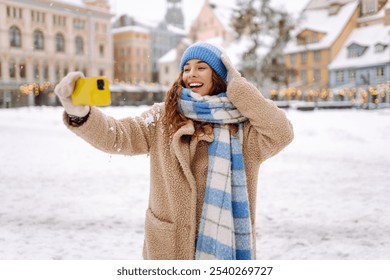 Smiling woman in winter clothing taking selfie through smartphone.  Selfie time. Holidays, rest, blogging - Powered by Shutterstock