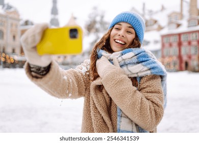 Smiling woman in winter clothing taking selfie through smartphone.  Selfie time. Holidays, rest, blogging - Powered by Shutterstock