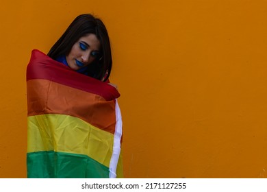 Smiling Woman Wrapped Rainbow Flag While Standing Against orange background