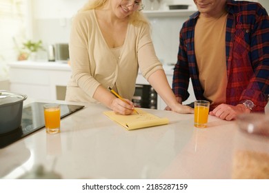 Smiling Woman Writing Shopping List For Husband Going To Grocery Store