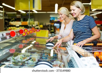 Smiling Women Buying Frozen Vegetables In Grocery Store