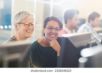 Smiling women at computer in adult education classroom - Powered by Shutterstock