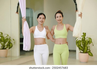 Smiling Women Practicing Aerial Yoga in Studio - Powered by Shutterstock