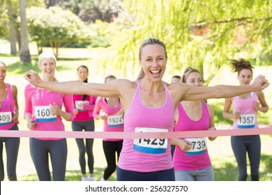 Smiling women running for breast cancer awareness on a sunny day
