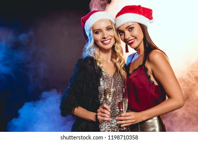 Smiling Women In Santa Hats With Champagne Glasses Posing On New Year Party 