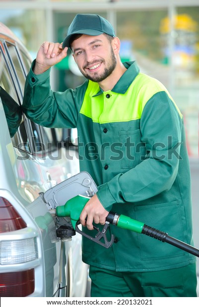 Smiling\
worker at the gas station, while filling a\
car