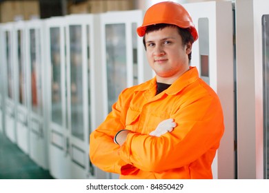 Smiling worker in orange workwear standing near vending machines