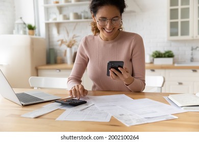 Smiling young 30s woman in eyewear looking at smartphone screen, feeling satisfied with fast secure online service, paying household bills taxes or insurance, managing budget, calculating expenses. - Shutterstock ID 2002100264