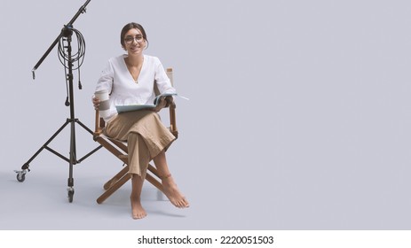 Smiling Young Actress Sitting On The Director's Chair And Reading The Play Script: Drama School, Film Industry And Video Production Concept