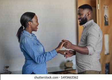 Smiling young African American couple playfully dancing hand in hand together in their living room at home - Shutterstock ID 1493463362