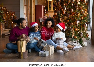 Smiling young African American family with small children unpack boxes with New Year gifts together. Happy biracial parents with kids open gifts presents on Christmas morning. Winter holiday concept. - Powered by Shutterstock