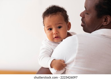 Smiling Young African American Father Holding Cute Infant Baby On Hands, Caring Black Dad Cuddling His Adorable Little Son Or Daughter While Bonding Together At Home, Closeup Portrait, Copy Space