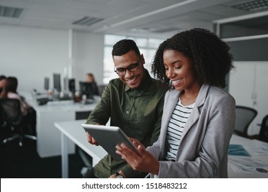 Smiling young african american professional businessman and businesswoman together working online with a digital tablet in office - Powered by Shutterstock