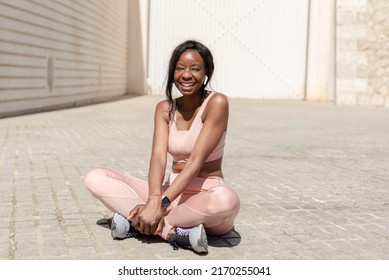 A Smiling Young African American Woman Sitting On The Ground Resting After A Workout