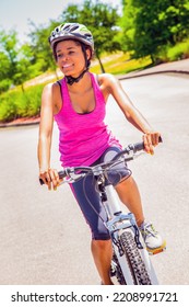 Smiling Young African American Woman Having Fun Outdoors And Keeping Fit On Solo Bike Ride Along Suburban Street