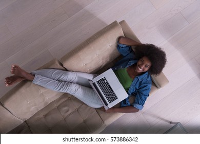 Smiling Young African American Woman Using Laptop While Relaxing On Sofa At Luxury Home Top View