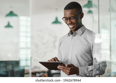 Smiling young African businessman using a digital tablet at work - Powered by Shutterstock