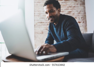 Smiling Young African Man Making Video Call With Friends While Sitting On Sofa At His Modern Coworking Place.Concept Of Happy Business People.Blurred Background, Flare Effect