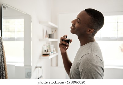 Smiling Young African Man Spraying On Cologne In His Bathroom