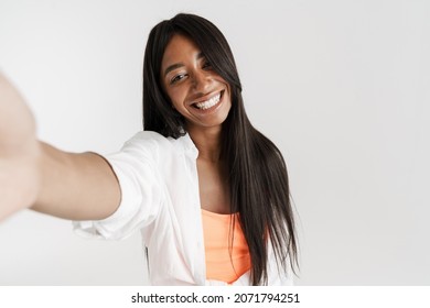Smiling young african woman with long dark hair standing over white wall background taking a selfie - Shutterstock ID 2071794251