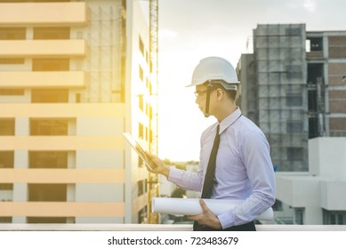 smiling young architect or engineering builder in hard hat with tablet over group of builders at construction site, architect watching some a construction, business, building, industry, people concept