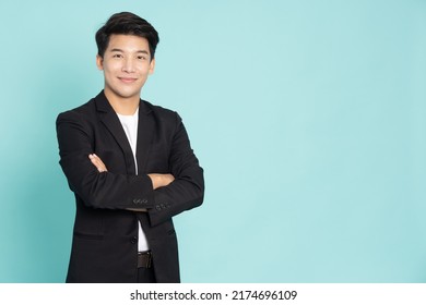 Smiling young Asian businessman with arms crossed isolated on green background - Shutterstock ID 2174696109